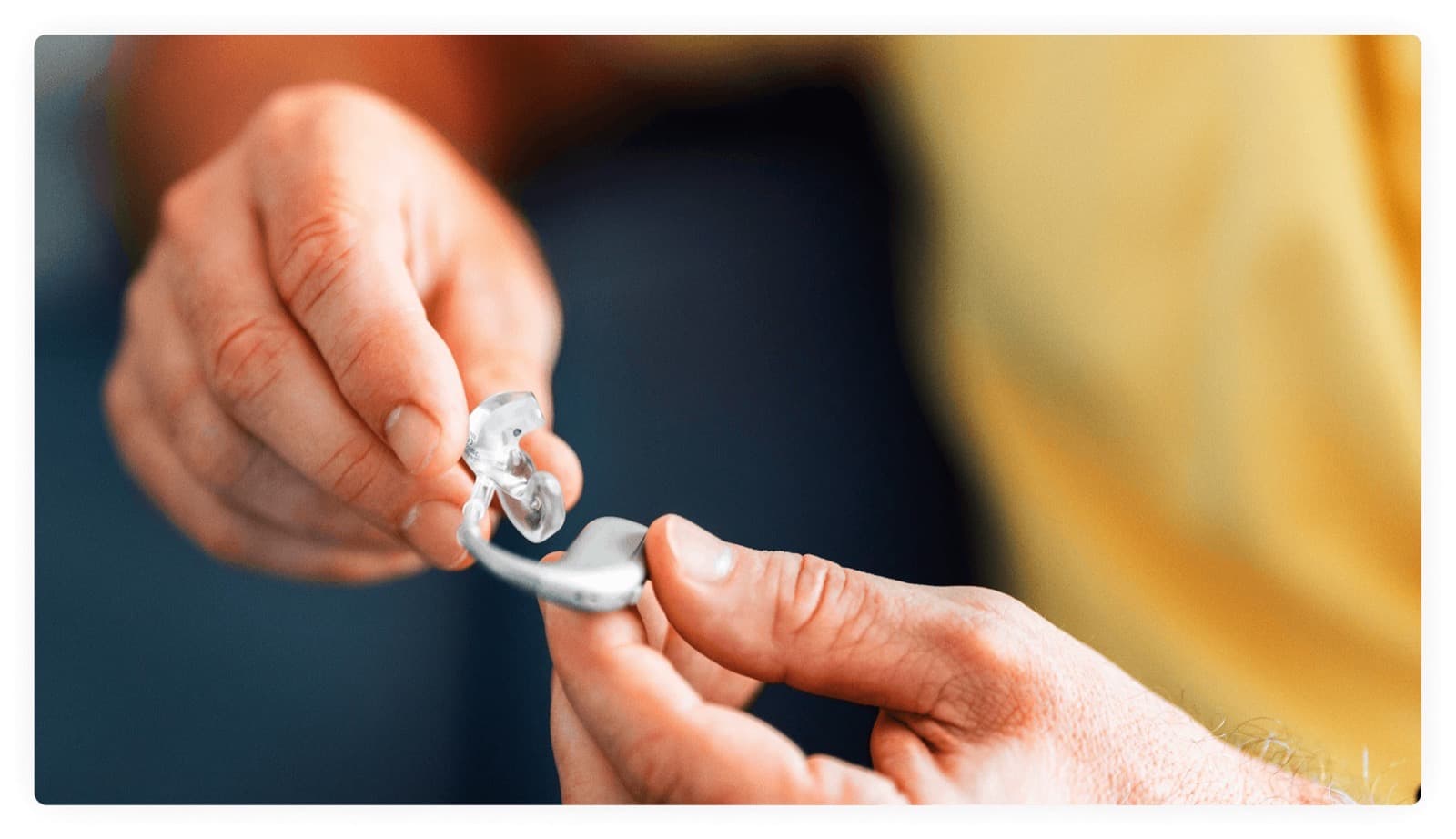 Hands holding a hearing aid