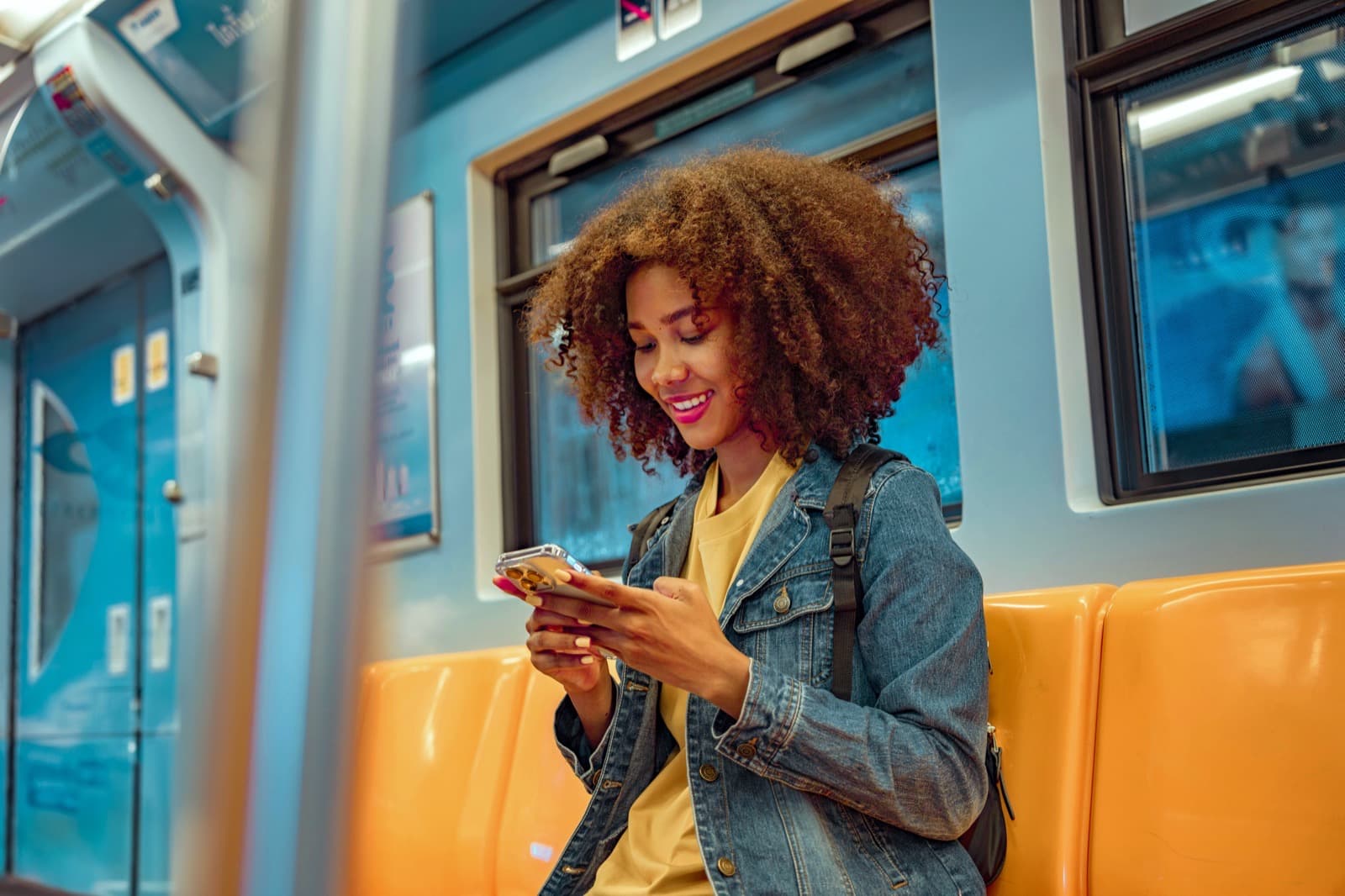 A smiling woman sits on the metro