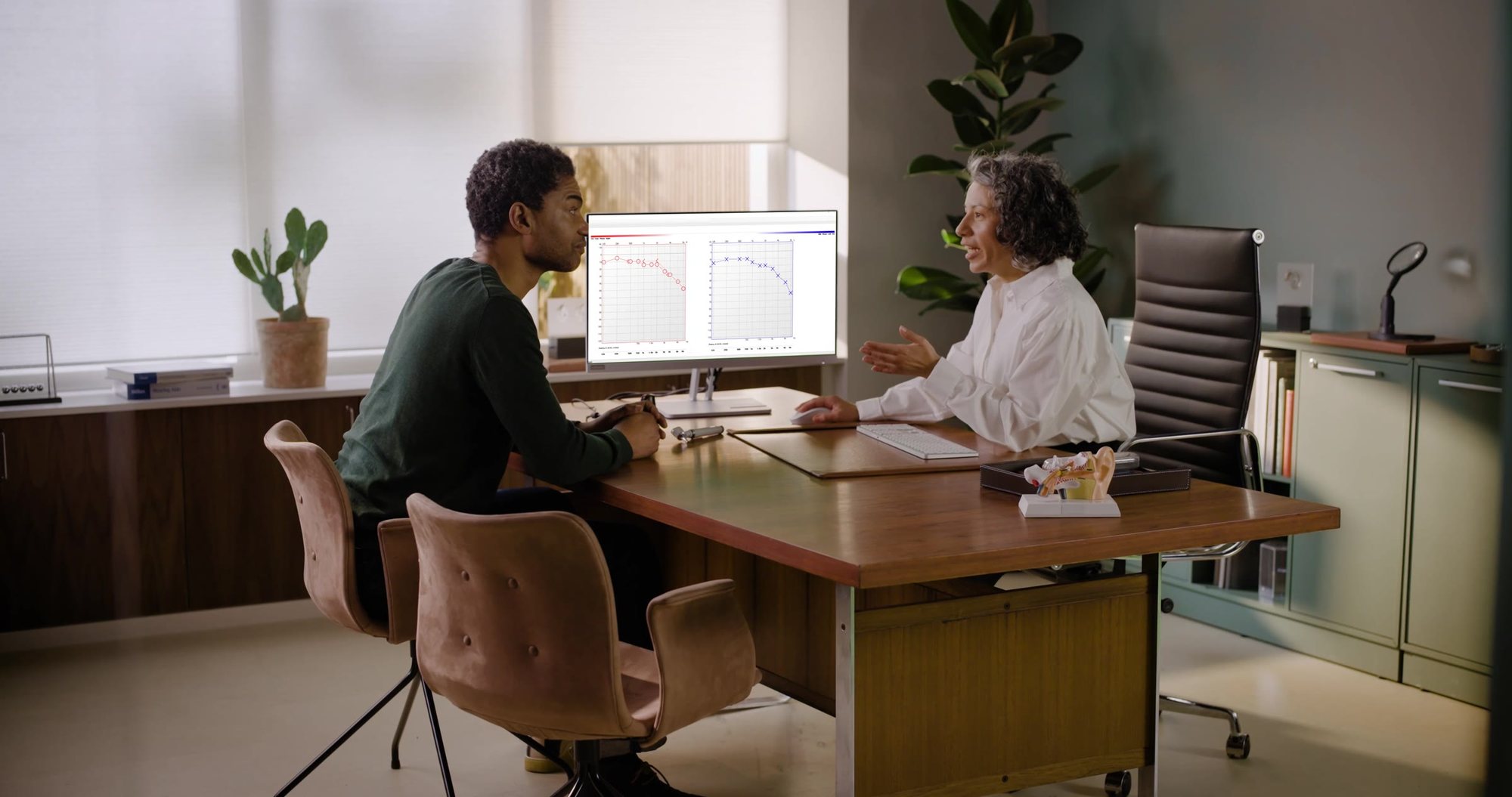 A hearing care professional reviewing results on screen with a client