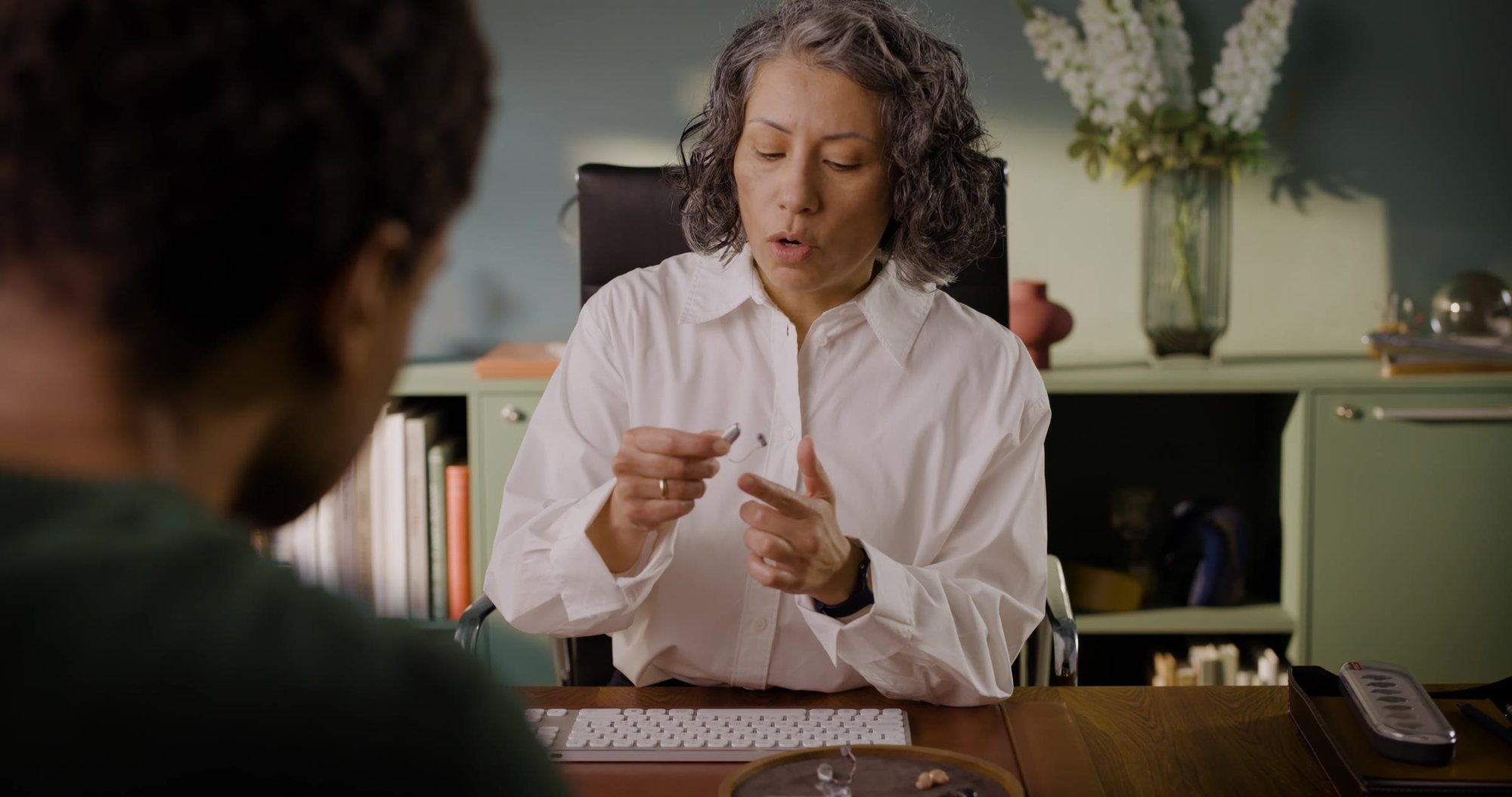A hearing care professional showing a hearing aid to a client