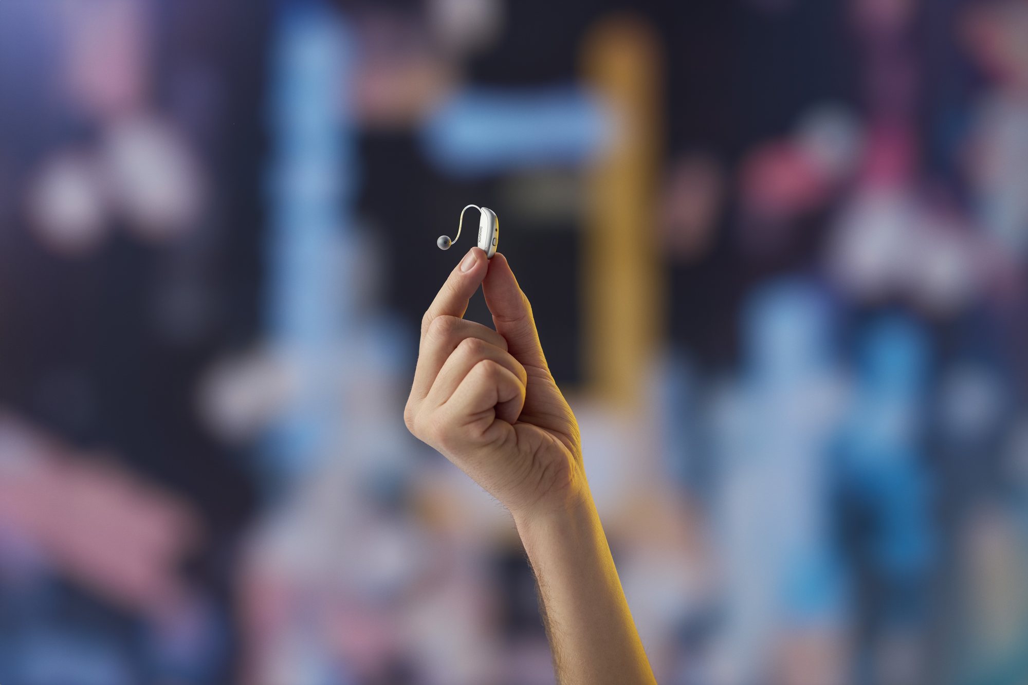 A Danavox hearing aid held between the fingers